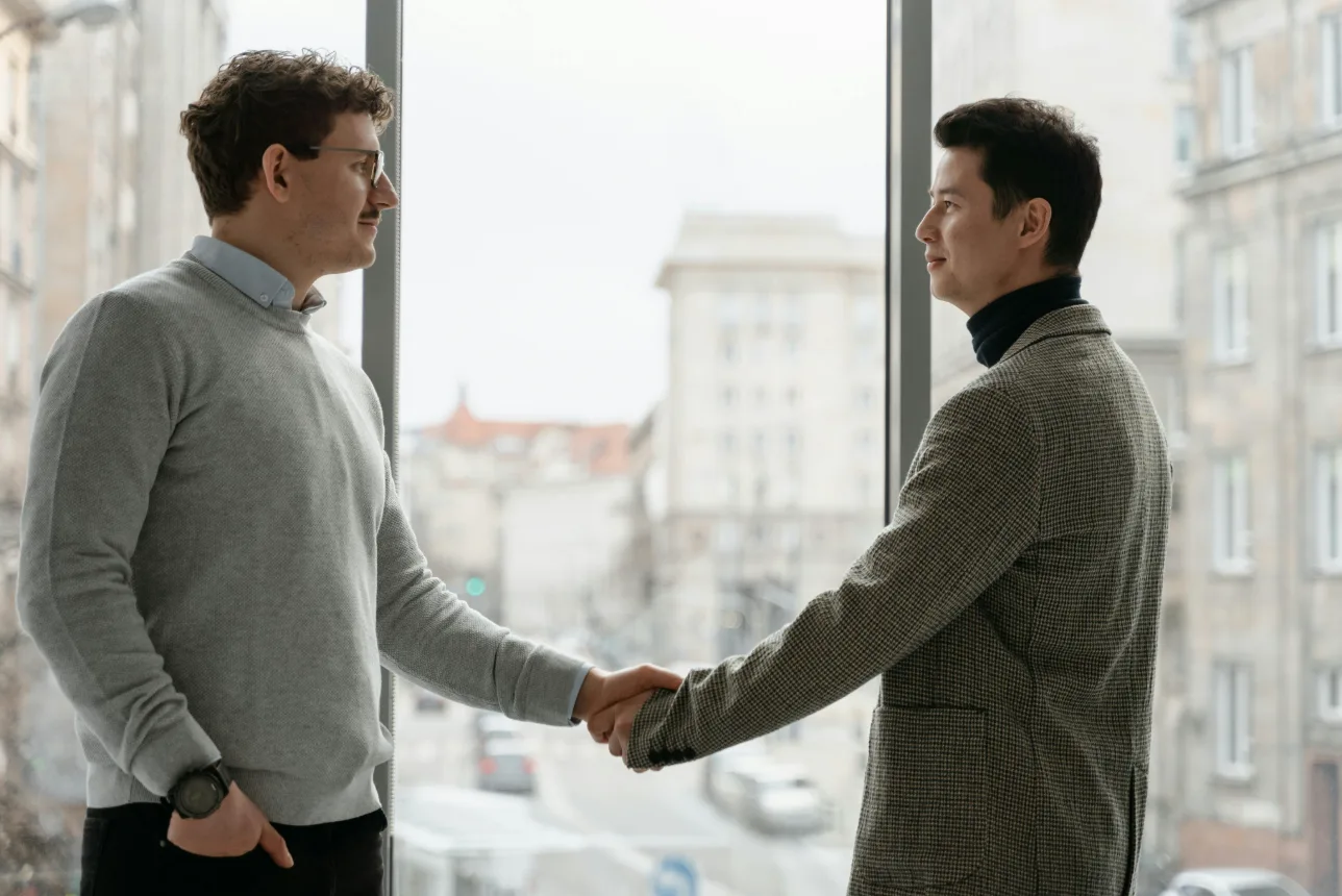 Dois homens dão um aperto de mão junto a uma janela