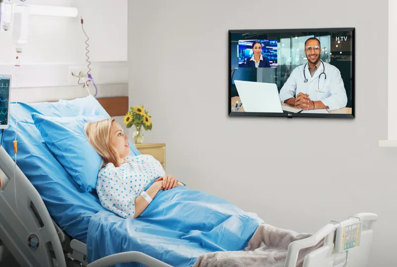 Doente numa cama de hospital com televisão na parede